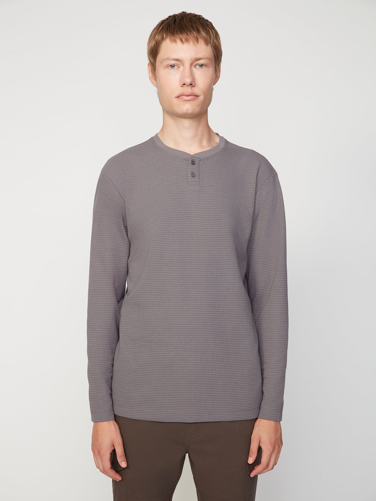 A young person with short light brown hair faces forward, wearing the PROJEK RAW MENS LONG SLEEVE HENLEY GRID JERSEY and dark pants, standing against a plain white background.