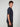A young man with short curly brown hair models the PROJEK RAW MENS SHORT SLEEVE SCUBA JERSEY RELAXED FIT TSHIRT in navy blue and black pants, standing sideways against a plain light gray background, ideal for casual wear.