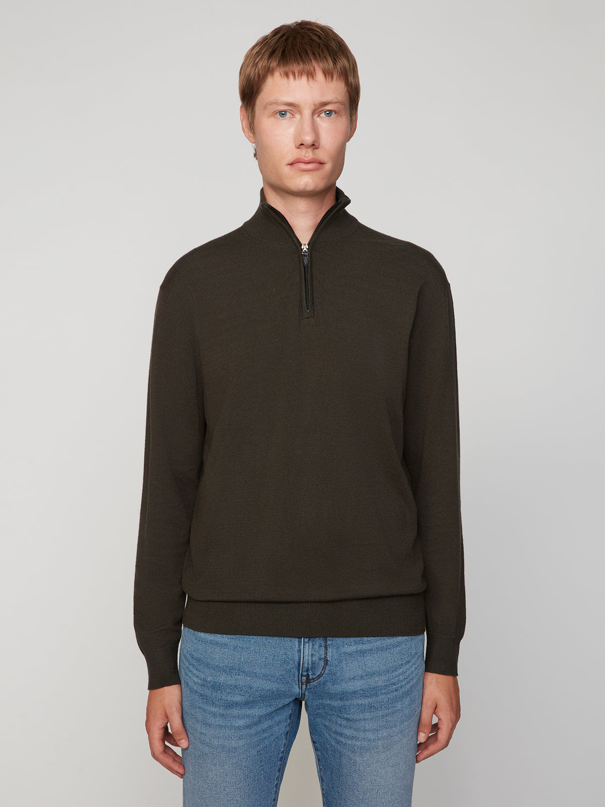A person with short light brown hair wears a PROJEK RAW MENS 1/4-ZIP CASHMERE TOUCH SWEATER and blue jeans, standing against a plain light gray background and looking directly at the camera.