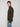 A young man with short auburn hair models the PROJEK RAW MENS 1/4-ZIP CASHMERE TOUCH SWEATER in dark olive and light blue jeans, standing sideways and looking at the camera against a plain light background.
