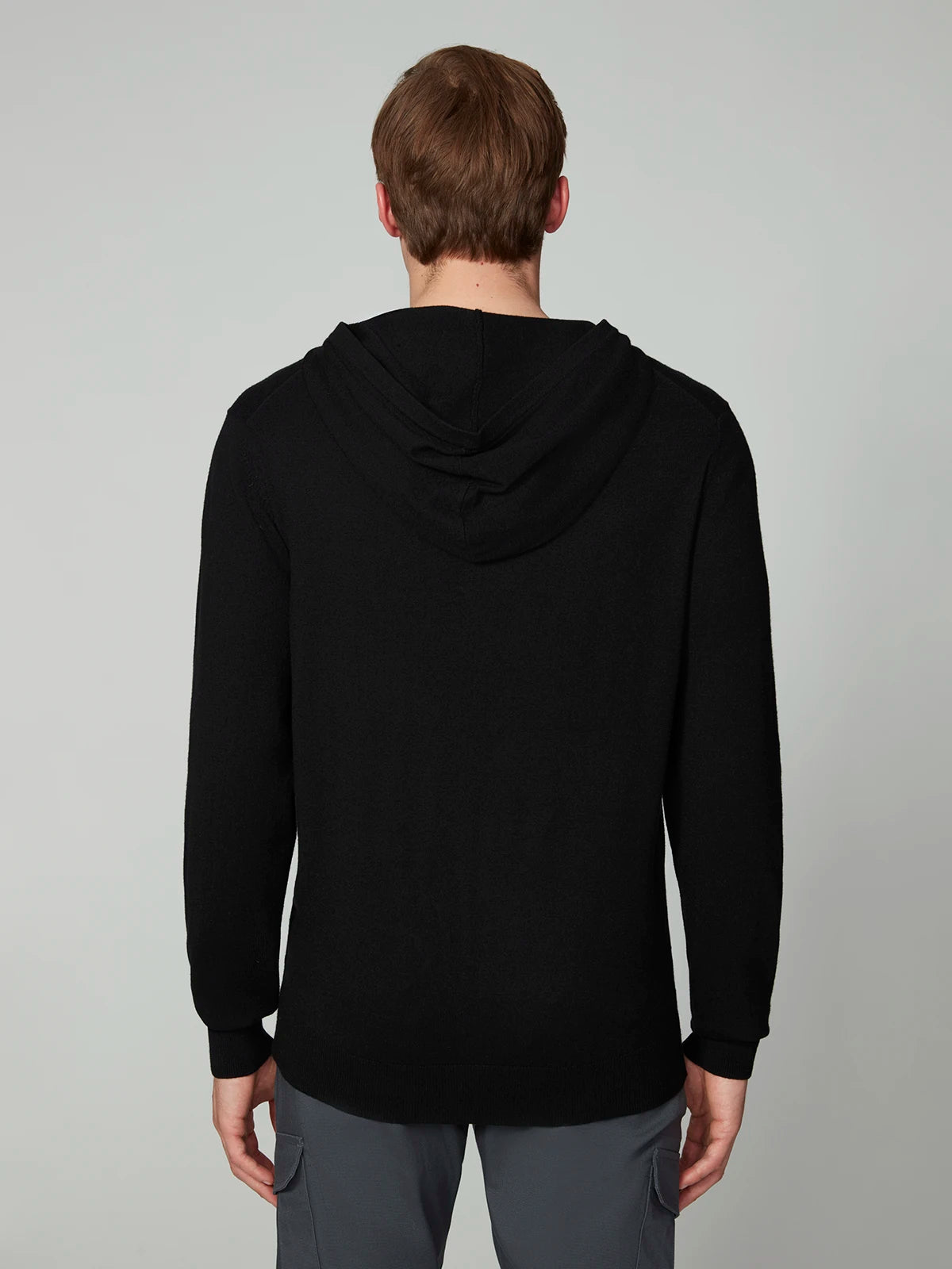 A person with short light brown hair is shown from behind, wearing a PROJEK RAW MENS CASHMERE TOUCH HOODIE SWEATER and gray pants against a plain light gray background.