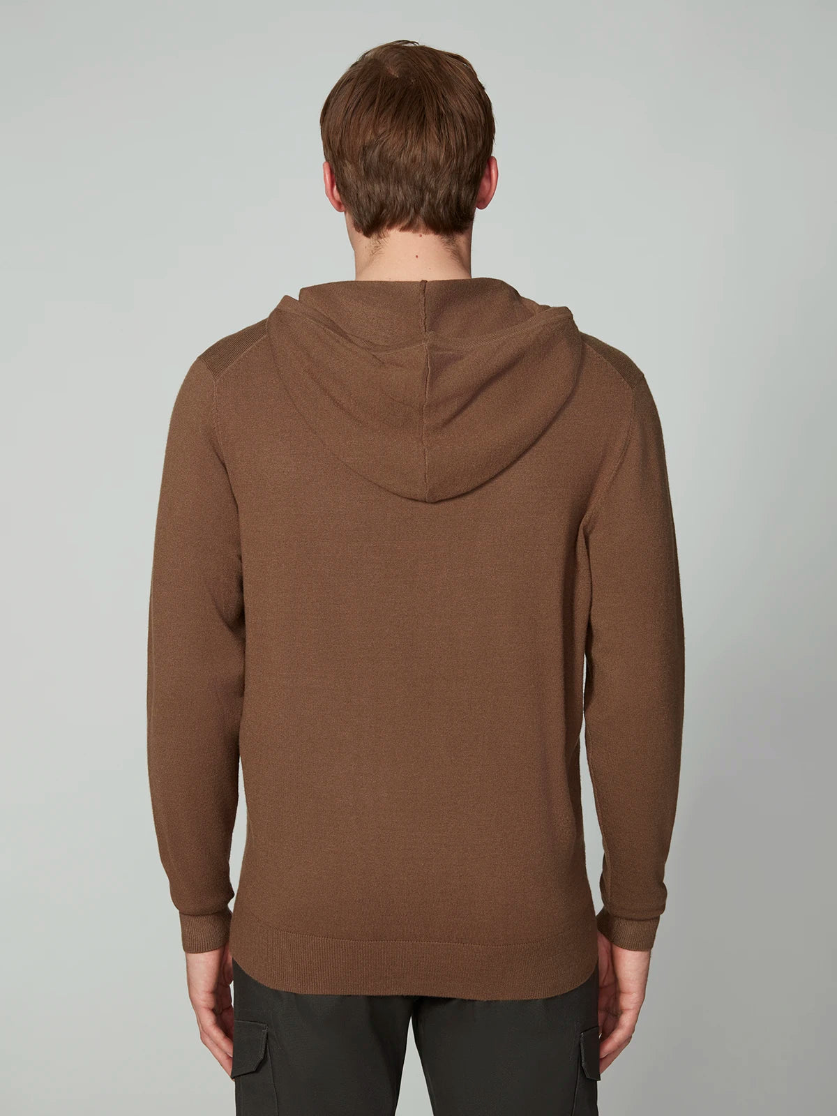 A person with short brown hair, wearing a PROJEK RAW MENS CASHMERE TOUCH HOODIE SWEATER and dark pants, stands with their back to the camera against a plain light gray background.