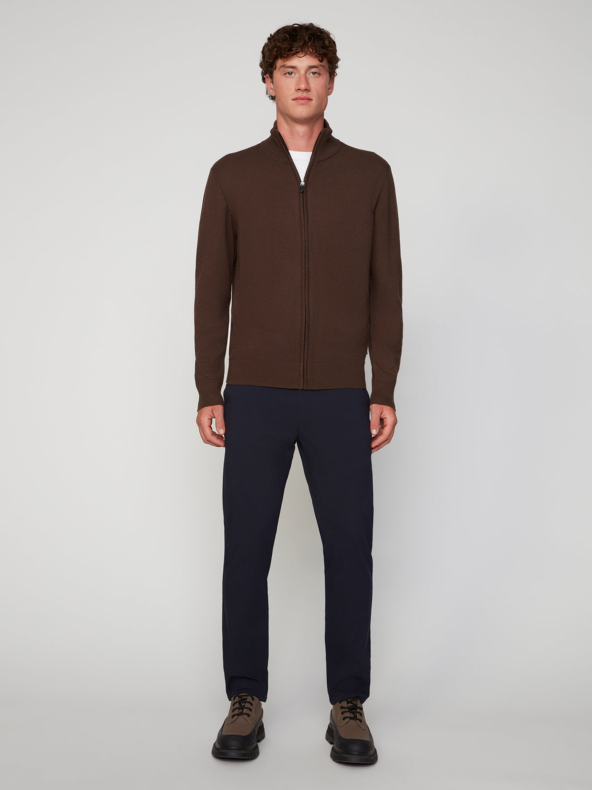 A man faces forward against a light background, wearing the PROJEK RAW MENS ZIP-UP CASHMERE TOUCH SWEATER, navy pants, and brown shoes.
