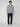 A person stands facing forward, wearing the PROJEK RAW MENS ZIP-UP CASHMERE TOUCH SWEATER in light gray over a white shirt, paired with dark slim pants and white sneakers, set against a plain light gray background.