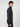 A young man with curly hair stands sideways, facing left, wearing a dark PROJEK RAW MENS ZIP-UP CASHMERE TOUCH SWEATER and dark pants against a plain white background.