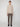 A person stands against a plain light background, wearing a beige PROJEK RAW MENS CREW NECK CASHMERE TOUCH SWEATER, brown plaid trousers, and black shoes.