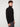 A young man with curly brown hair models the PROJEK RAW MENS CHENILLE MOCK NECK SWEATER in black with gray pants, standing sideways and looking at the camera against a plain white background.