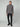 A man stands against a plain light background wearing the PROJEK RAW MENS CHENILLE MOCK NECK SWEATER in gray, paired with black pants and black sneakers. He faces forward with a neutral expression and relaxed posture.