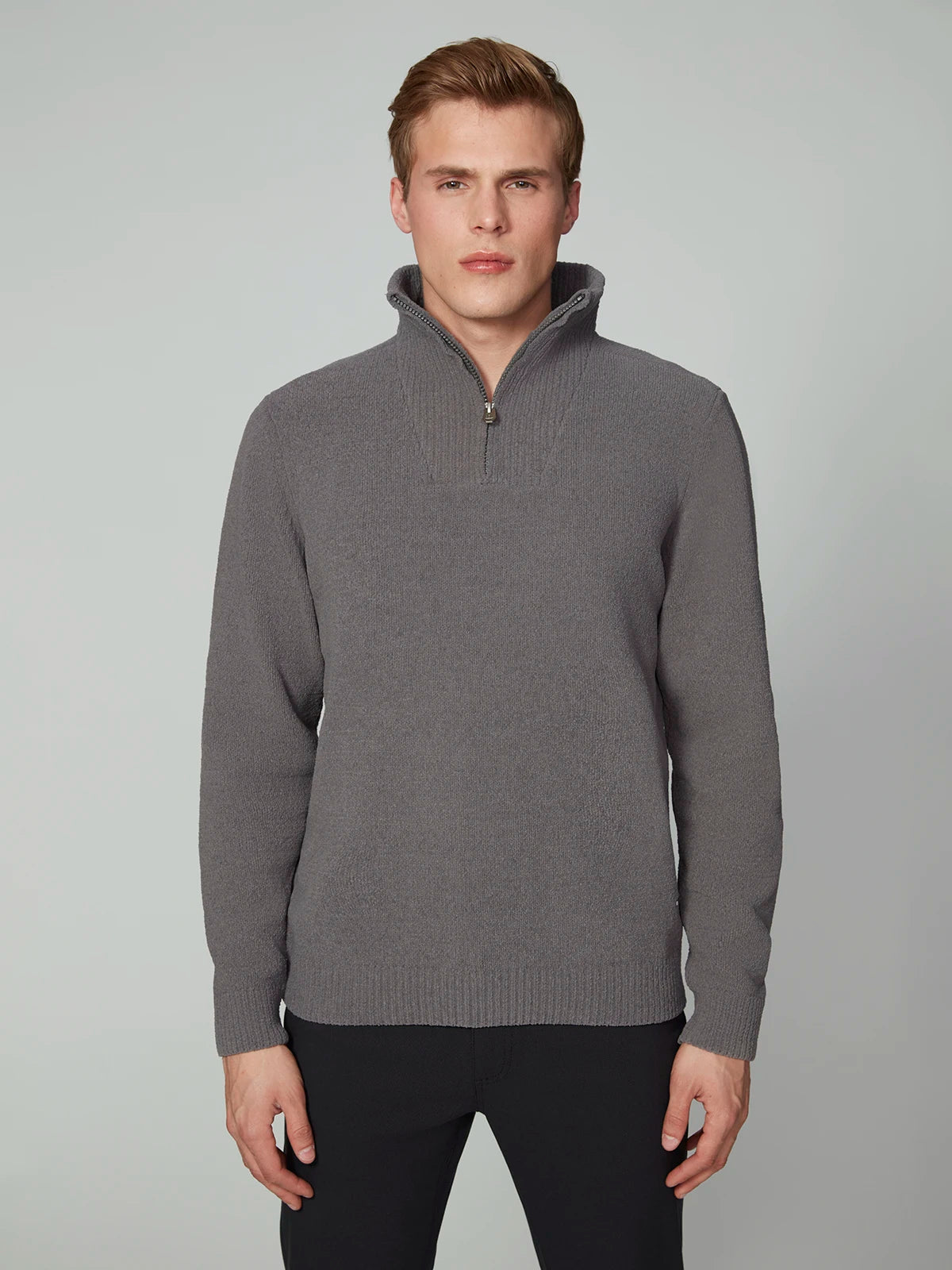 A young man with short light brown hair models the MENS CHENILLE MOCK NECK SWEATER by PROJEK RAW and black pants, standing against a plain light gray background, looking straight at the camera with a neutral expression.