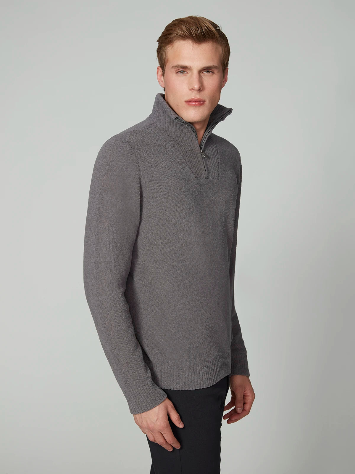 A young man with short, light brown hair wears a PROJEK RAW MENS CHENILLE MOCK NECK SWEATER in grey and black pants, standing against a plain light grey background.