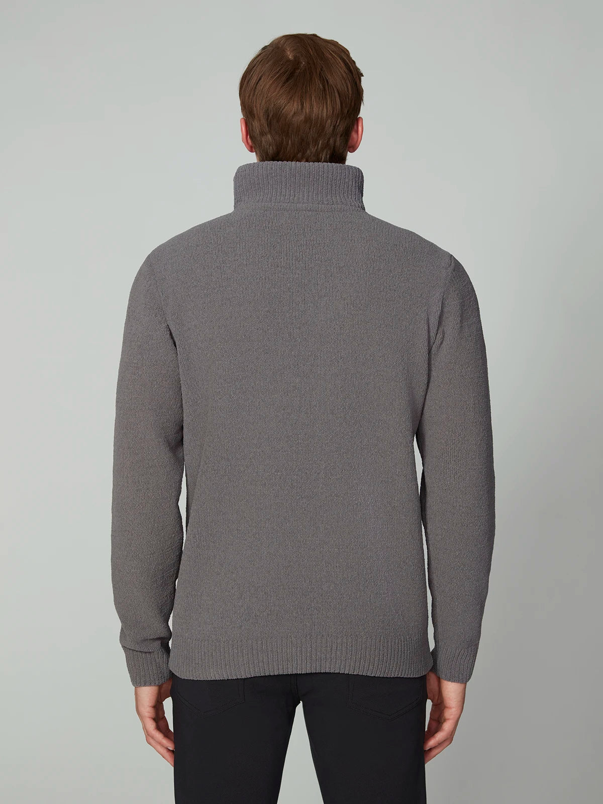 A person with short brown hair is seen from behind wearing the PROJEK RAW MENS CHENILLE MOCK NECK SWEATER in grey and black pants, standing against a plain light grey background.