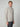 A young man with short light brown hair wears the PROJEK RAW MENS CHENILLE MOCK NECK SWEATER in light gray and dark gray pants. He stands against a plain light background, looking slightly to the side.