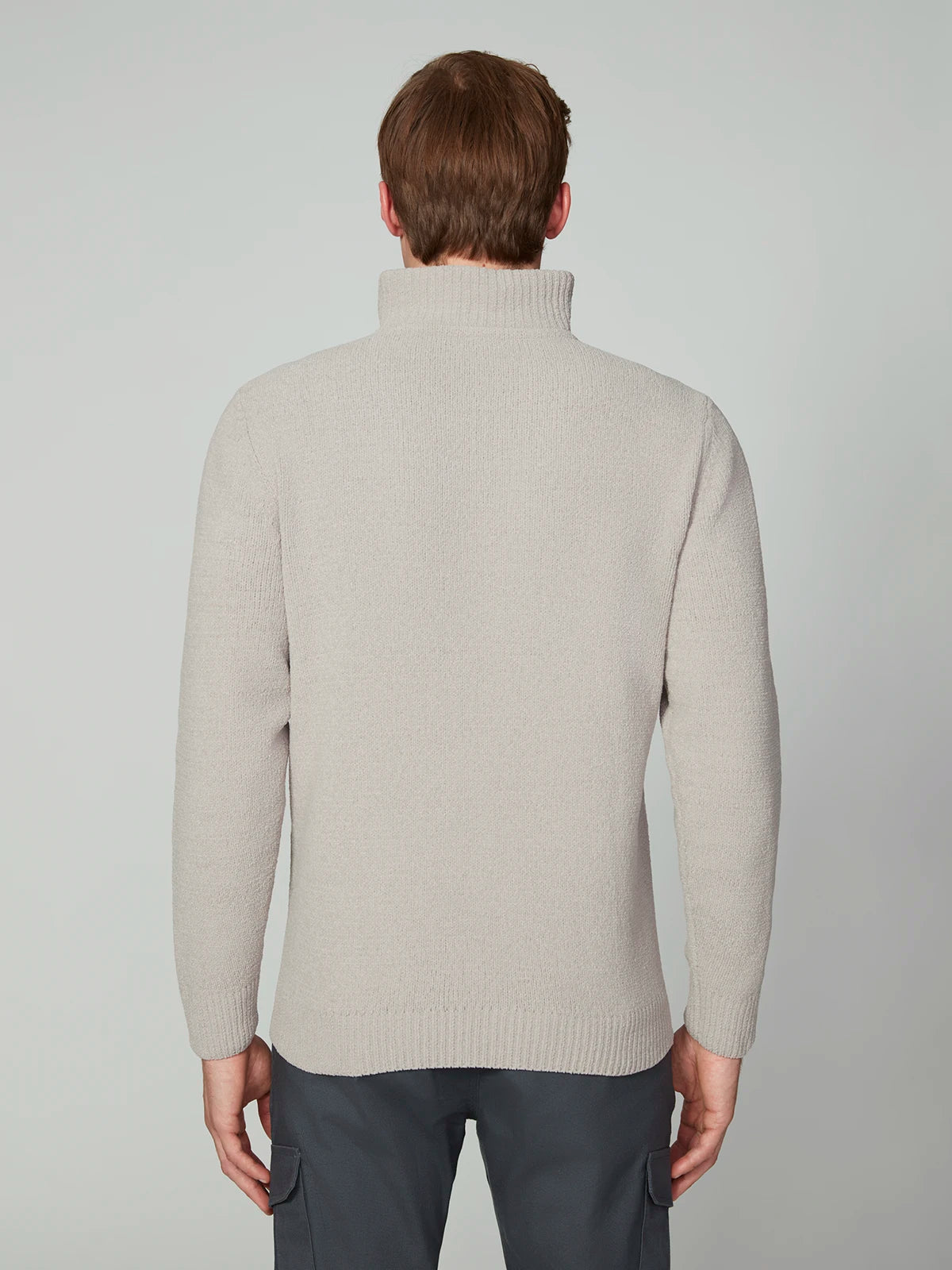 A person with short brown hair, seen from behind, is wearing a PROJEK RAW MENS CHENILLE MOCK NECK SWEATER in light beige and dark gray pants against a plain light background.