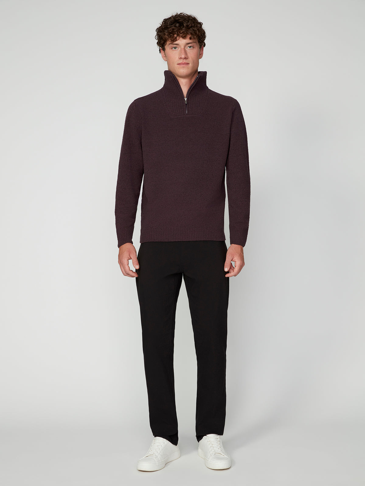 A young man stands facing forward in a PROJEK RAW MENS CHENILLE MOCK NECK SWEATER, paired with black pants and white sneakers, against a plain light gray background.