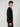 A young man with curly brown hair stands sideways, facing left. Hes wearing a PROJEK RAW MENS SHAKER RIB KNIT SWEATER and dark pants, posing against a plain light gray background.