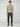 A young man with short curly hair faces forward, wearing a beige PROJEK RAW MENS SHAKER RIB KNIT SWEATER, dark olive cargo pants, and beige lace-up shoes against a plain light gray background.