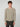 A young man with curly brown hair wears the PROJEK RAW MENS SHAKER RIB KNIT SWEATER in beige and dark pants, standing against a plain light gray background with a neutral expression.