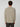 A man with short curly hair, seen from behind, wears the PROJEK RAW MENS SHAKER RIB KNIT SWEATER in light beige and dark pants, standing against a plain light gray background.