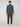 A man faces the camera in a PROJEK RAW MENS 1/4 ZIP JACQUARD KNIT MOCK NECK SWEATER, dark brown pants, and white sneakers against a plain light gray background.