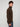 A young man with curly brown hair stands sideways against a plain light background, wearing blue jeans and a PROJEK RAW MENS CHENILLE MOCK NECK SWEATER, looking at the camera.