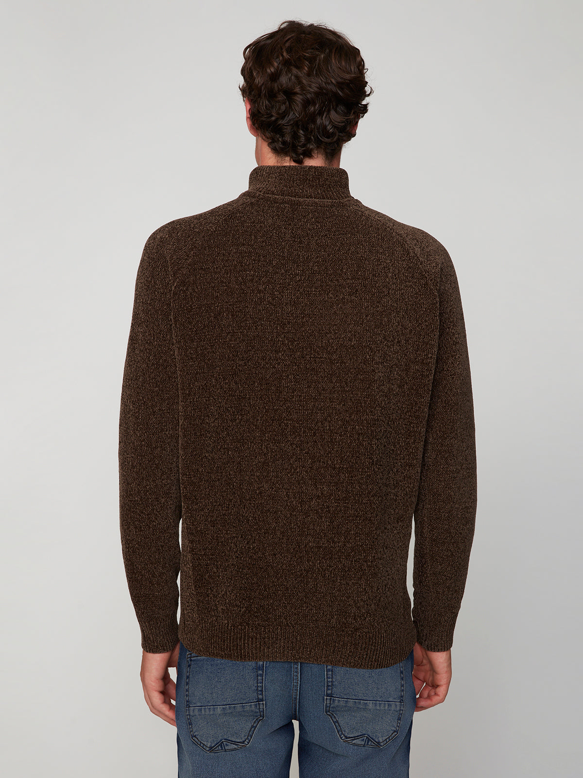 A person with short brown hair, wearing the PROJEK RAW MENS CHENILLE MOCK NECK SWEATER and blue jeans, stands with their back to the camera against a plain light gray background.