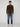 A man stands against a plain light gray background, wearing a brown PROJEK RAW MENS CHENILLE MOCK NECK SWEATER, blue jeans, and white sneakers. He faces forward with his arms relaxed at his sides.