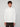 A young man with curly brown hair wears a white PROJEK RAW MENS CHENILLE MOCK NECK SWEATER and dark pants, standing against a plain light gray background, looking directly at the camera with a neutral expression.