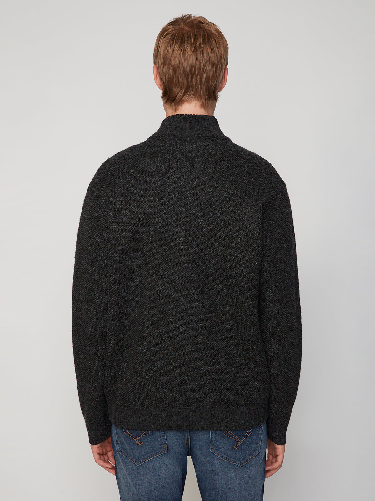 A man with short, light brown hair wears the PROJEK RAW MENS FULL ZIPPED KNIT SWEATER BONDED POLAR FLEECE in dark color and blue jeans, shown from the back against a plain light background.