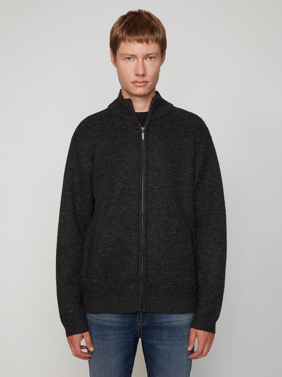 A person with short light brown hair wears the PROJEK RAW MENS FULL ZIPPED KNIT SWEATER BONDED POLAR FLEECE and blue jeans, standing facing forward against a plain light gray background.