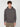 A young man with curly brown hair models the PROJEK RAW MENS LONG SLEEVE CARBON PEACHED FLEECE HOODIE in dark gray, featuring a front pocket, paired with tan cargo pants, against a light gray background.