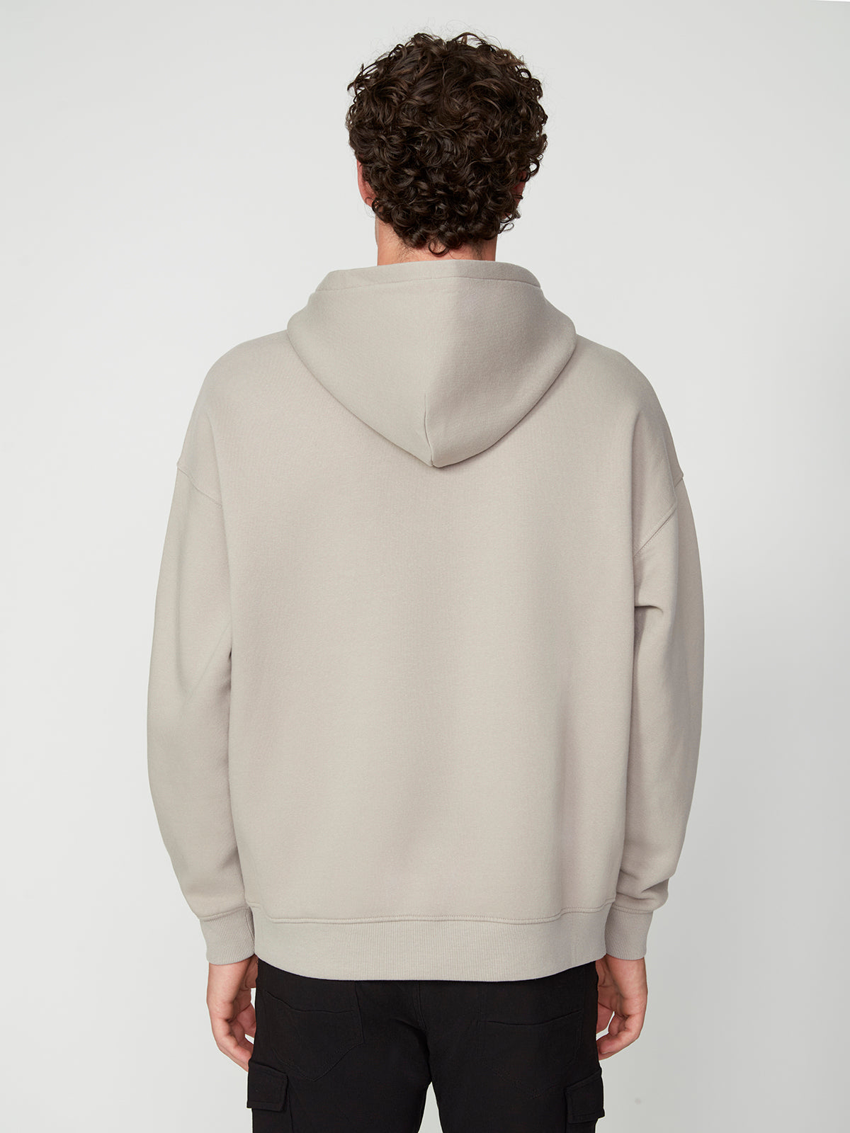 A person with curly hair faces away from the camera, wearing a PROJEK RAW MENS LONG SLEEVE CARBON PEACHED FLEECE HOODIE in light gray and black pants against a plain white background.