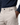 A person wears the PROJEK RAW SOLID BUNGEE CARGO PANT for men in light beige, crafted from Bungee stretch fabric, with one hand in the pocket. The pants feature utility pockets, belt loops, and a visible black button, paired with a navy blue shirt tucked in.