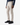 A person wearing the PROJEK RAW SOLID BUNGEE CARGO PANT for men in light beige, featuring utility pockets and crafted from Bungee stretch fabric, pairs them with a navy long-sleeve shirt and black sneakers while standing against a plain white background.