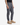 A person is shown from the waist down, standing against a plain white background, wearing PROJEK RAW SOLID BUNGEE PULL ON JOGGER pants in gray with a relaxed fit, paired with a black shirt and tan boots.
