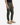 A person wearing the PROJEK RAW SOLID BUNGEE PULL ON JOGGER in olive green, styled with an adjustable waist, paired with a black shirt and beige lace-up boots, standing against a plain white background.