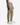 A person wearing the PROJEK RAW SOLID BUNGEE CARGO CLASSIC FIT JOGGER in light brown, featuring stretch fabrication and side cargo pockets, paired with a white ribbed tank top and white sneakers, stands against a plain white background.