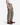 A person wearing PROJEK RAW’s SOLID BUNGEE LOOSE FIT CARGO PANT for men in taupe, featuring utility pockets, pairs them with a white tank top and brown leather boots while standing against a plain white background. Only the lower torso, legs, and arms are visible.