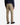 A person wearing PROJEK RAW SOLID BUNGEE 5-POCKET RELAXED FIT PANTS, a blue plaid shirt, and black sneakers is standing with their back to the camera against a white background.
