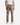 A person is standing with their back to the camera against a plain white background, wearing a white T-shirt, PROJEK RAW SOLID BUNGEE 5-POCKET RELAXED FIT PANTS in tan, and white sneakers.