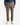 A person wearing a blue denim shirt, white sneakers, and PROJEK RAW SOLID BUNGEE 5-POCKET RELAXED FIT PANTS in light brown stands against a plain white background. Only the body from shoulders to feet is visible.