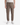 A person is wearing the PROJEK RAW SOLID BUNGEE CARGO RELAXED FIT PULL ON JOGGER in taupe, featuring stretch fabrication and drawstrings, paired with white sneakers and a white t-shirt, while standing against a white background.