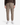 A model, shown from the shoulders down against a plain white background, is wearing the PROJEK RAW MEN’S SOLID BUNGEE RELAXED FIT CARGO JOGGER in taupe, styled with utility-inspired side pockets, paired with a brown sweater and white sneakers.