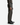 A person wearing PROJEK RAW BRUSHED BACK BUNGEE 5-POCKET PANTS in dark brown, paired with a matching brown sweater, a black belt, and black dress shoes, standing against a white background.