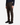 A person is standing against a plain white background wearing the PROJEK RAW CANVAS BUNGEE CLASSIC FIT PULL ON JOGGER in dark brown, styled with a tapered leg and adjustable drawcord, paired with a navy plaid shirt and black sneakers.