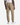 A person is standing facing away from the camera against a white background, wearing PROJEK RAW’s CANVAS BUNGEE CLASSIC FIT PULL ON JOGGER in tan, paired with a white T-shirt and white sneakers.