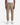 A person wearing PROJEK RAW’s CANVAS BUNGEE CLASSIC FIT PULL ON JOGGER in tan, paired with a white t-shirt and white sneakers, stands against a plain white background. The joggers feature drawstrings and elastic cuffs at the ankles.