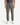 A person is seen wearing the KNIT CAVALRY TWILL RELAXED FIT CHINO PANTS by PROJEK RAW in olive green, featuring a drawstring waist and crafted from knit cavalry twill. Paired with a dark t-shirt and white sneakers, they stand against a plain white background. The modern tailoring of these relaxed-fit chinos from PROJEK RAW lends an elevated touch to their casual ensemble.