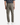 A person is standing facing away, wearing PROJEK RAW KNIT CAVALRY TWILL RELAXED FIT CHINO PANTS in gray, featuring an elastic waistband and back welt pockets, paired with a dark short-sleeve shirt and white sneakers.