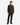 A man stands facing forward against a plain white background, wearing a brown button-up jacket over a dark shirt, black CORDUROY 5-POCKET STRAIGHT FIT BARU PANTS from PROJEK RAW with classic five-pocket styling, and black shoes.