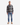 A man stands facing forward against a plain white background, wearing the PROJEK RAW PLAID FLANNEL SHIRT as a stylish layering piece, paired with light blue jeans and beige boots.